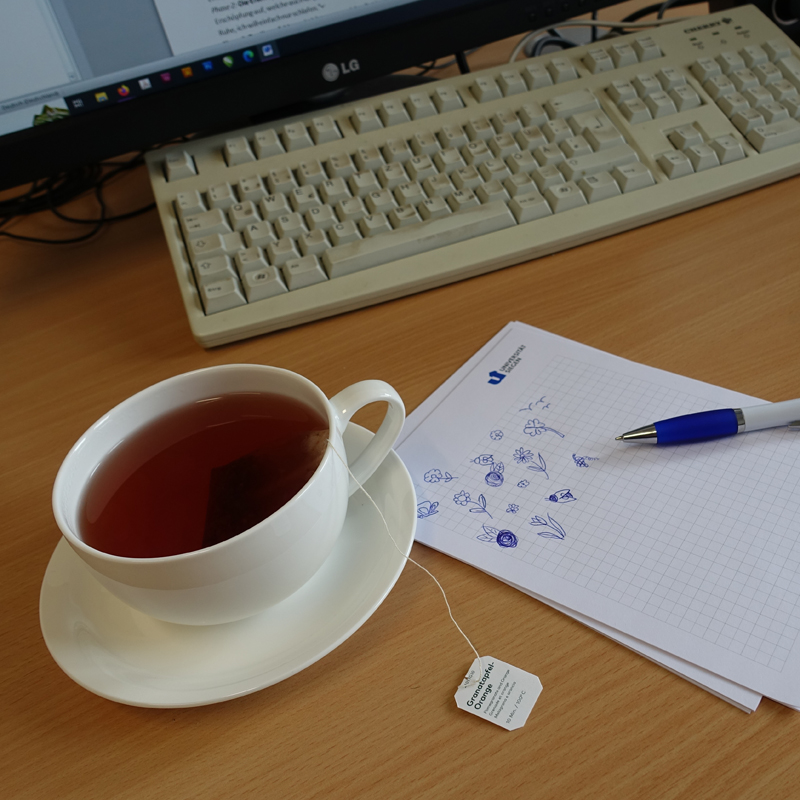 Keyboard, cup of tea, pen, notepad