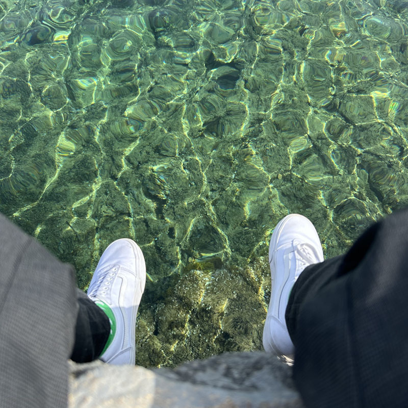 sea shoes pants water green white stones